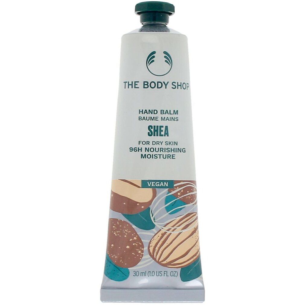 Creme-Tube mit Aufschrift "THE BODY SHOP HAND BALM SHEA". Abbildung von Nüssen. Vegan.