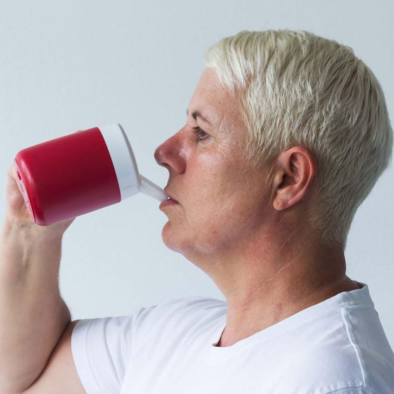 Person trinkt aus rotem Becher mit weißem Deckel und Schnabelaufsatz. Profilansicht.
