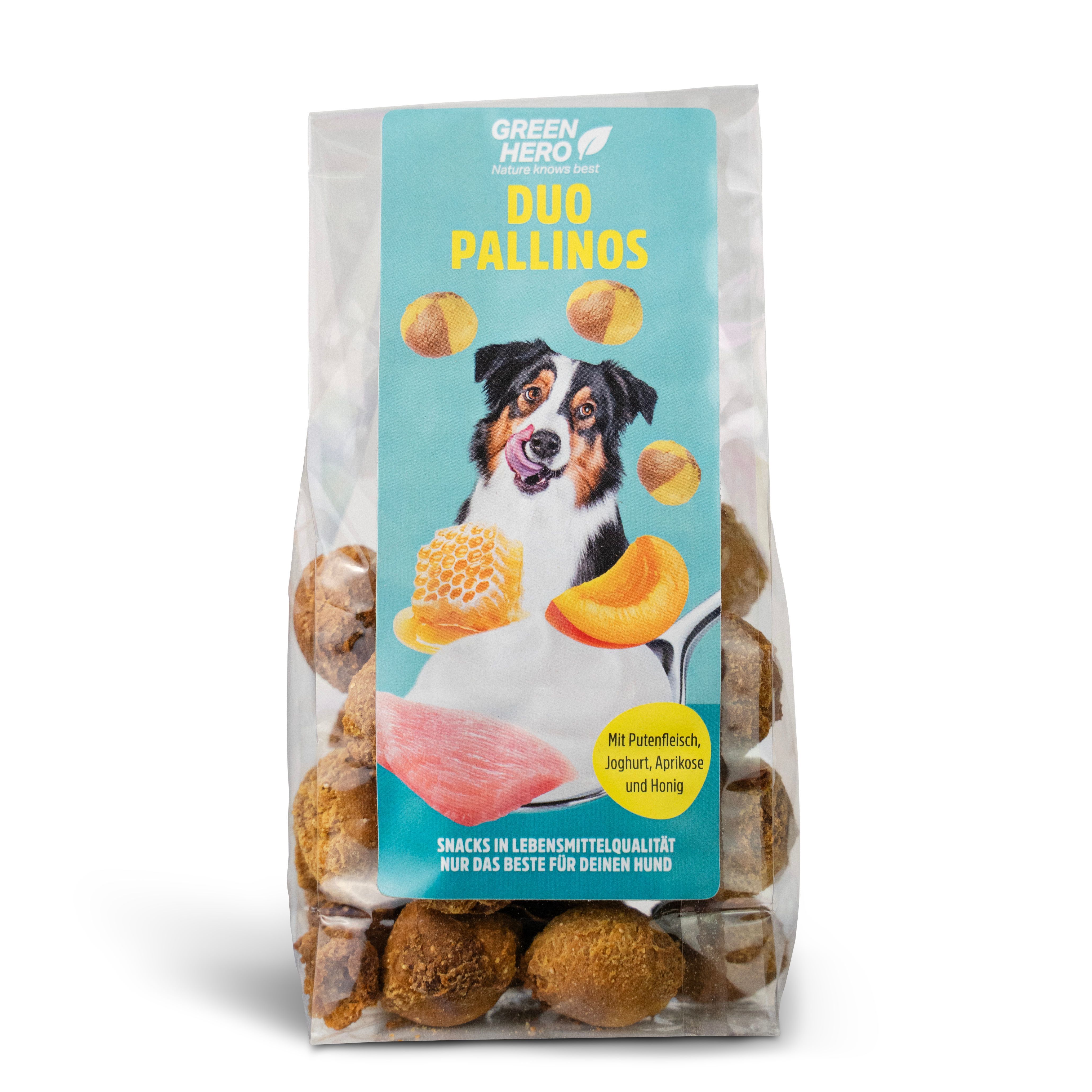 Transparente Verpackung mit Hundesnacks. Aufdruck: "Green Hero Duo Pallinos". Abbildung: Hund, Aprikosen, Honig, Joghurt und Putenfleisch.
