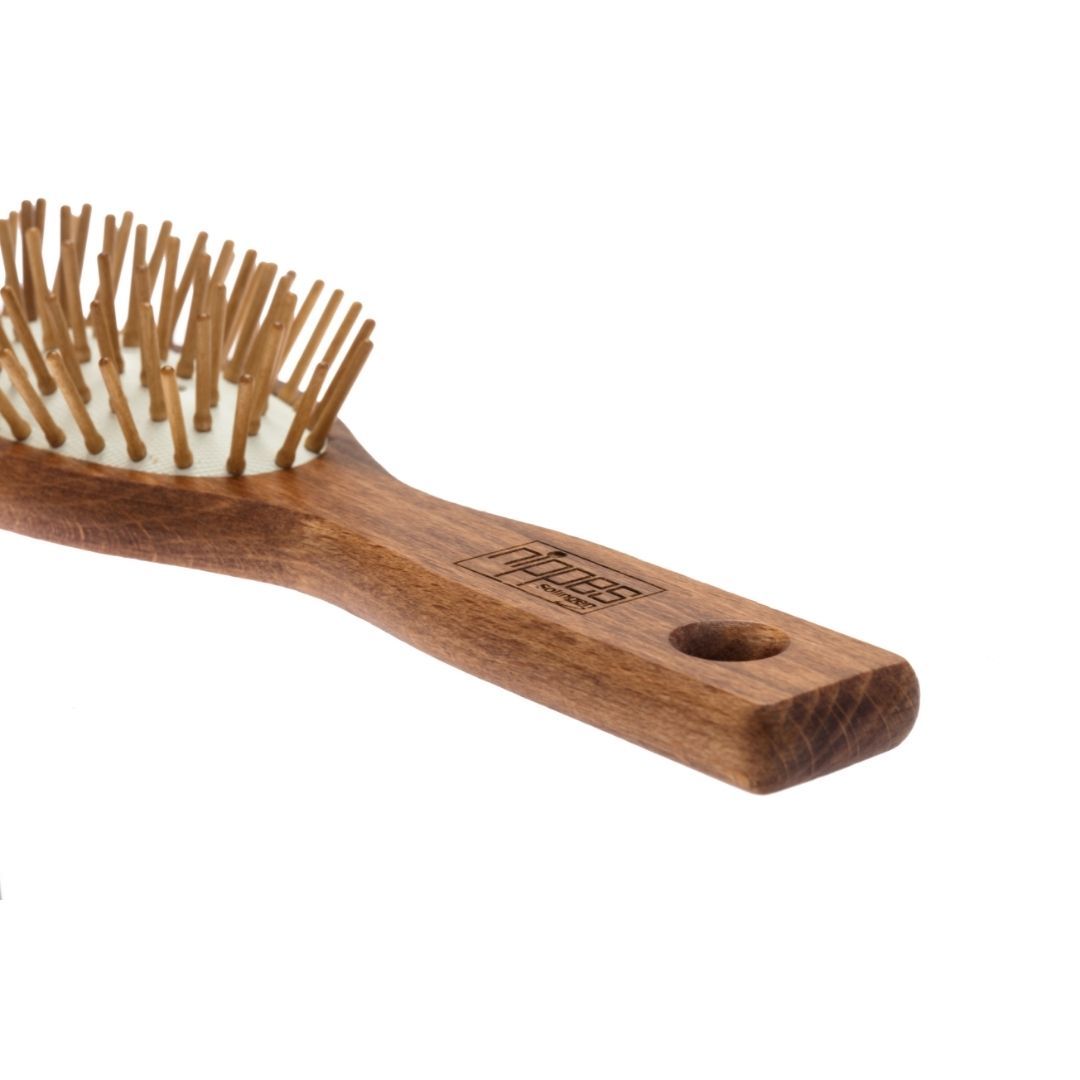 Nahaufnahme einer ovalen Haarbürste aus Holz mit Holzstiften. Griff mit Markenlogo und Loch.