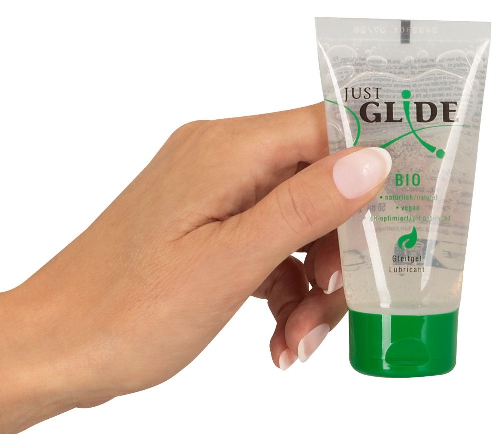 Eine Hand hält eine Tube Gleitgel mit grünem Verschluss. Aufschrift: Just Glide Bio. Vegan und pH-optimiert.