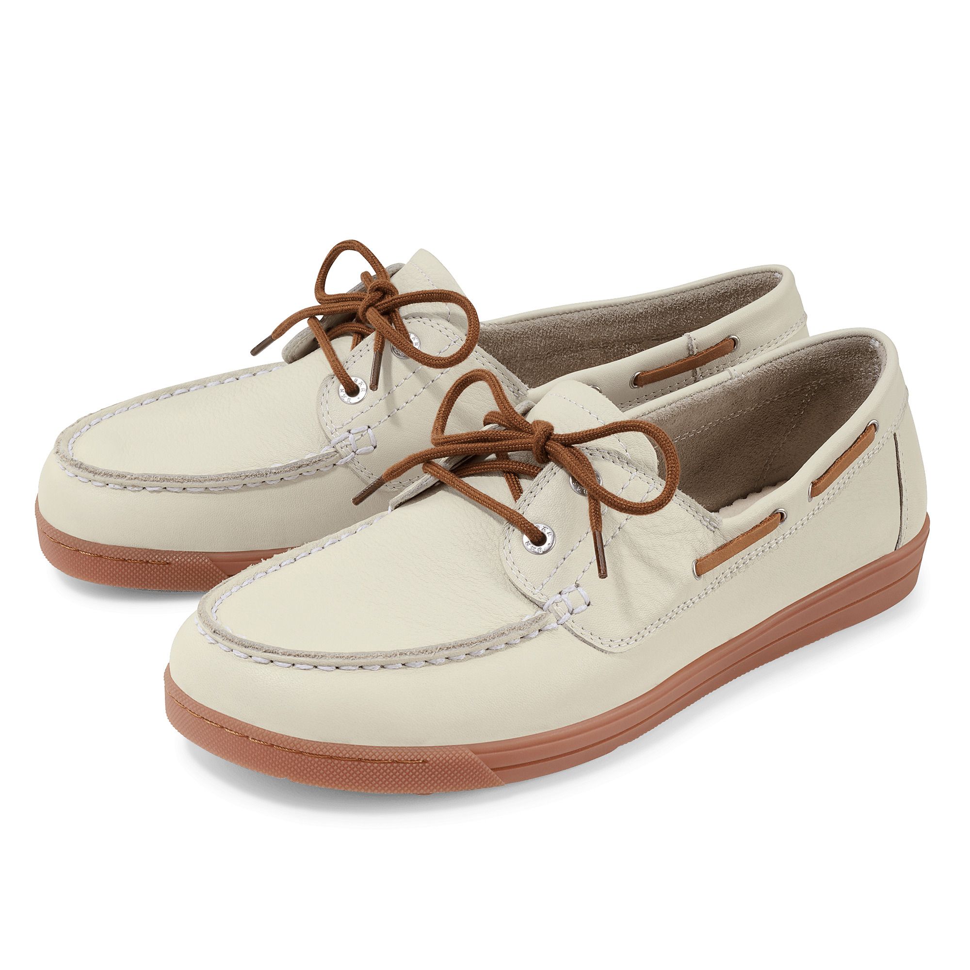 Zwei cremefarbene Schnürschuhe mit braunen Schnürsenkeln und Sohlen. Die Schuhe sind breit und haben helle Nähte.