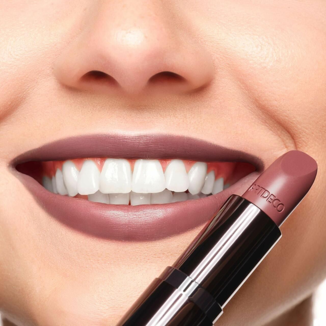 Person mit Lippenstift auf den Lippen. Der Lippenstift ist rosa und trägt die Aufschrift "ARTDECO".