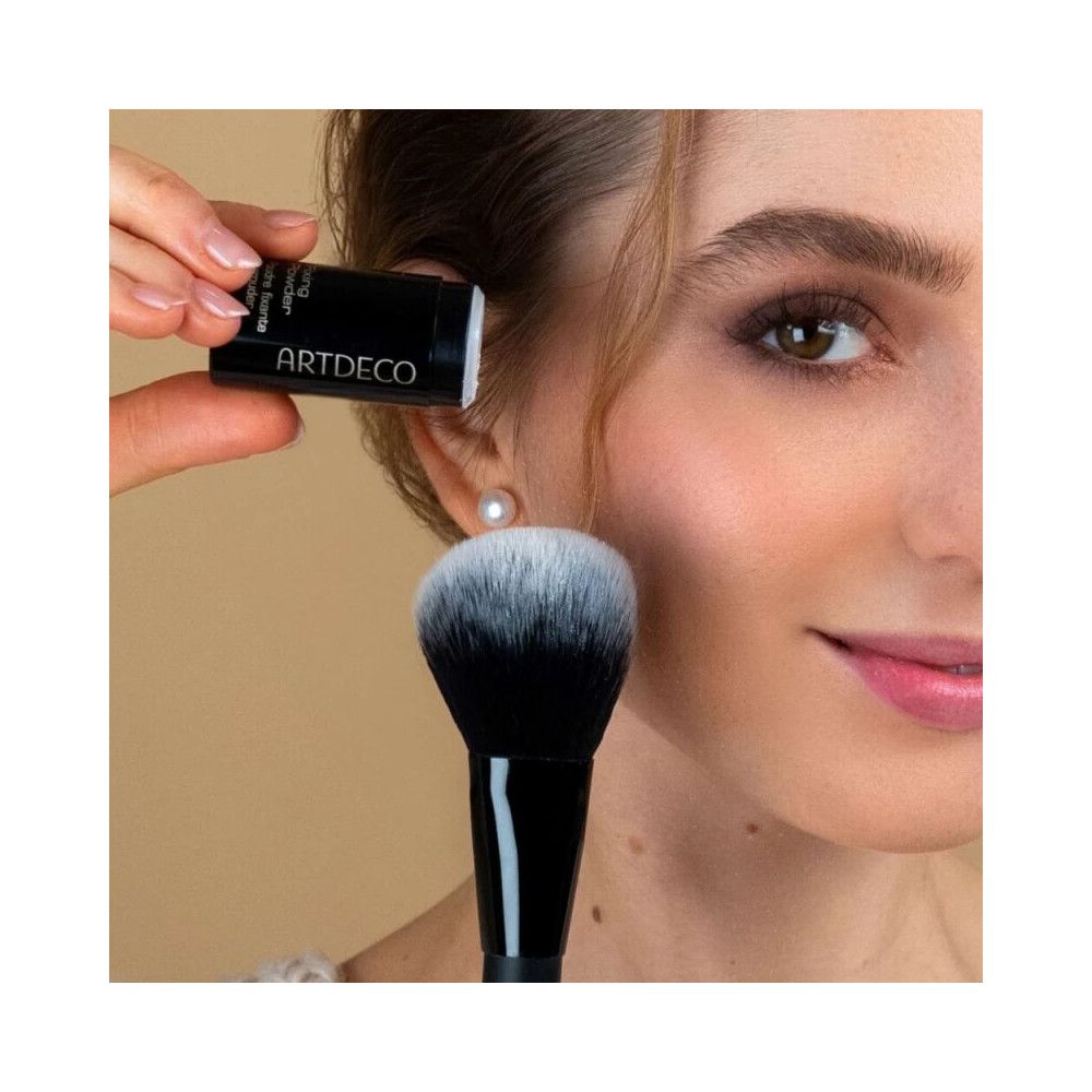 Person hält Dose und Pinsel. Aufschrift: ARTDECO, Fixing Powder, Poudre fixante, Fixierpuder. Großer Pinsel.