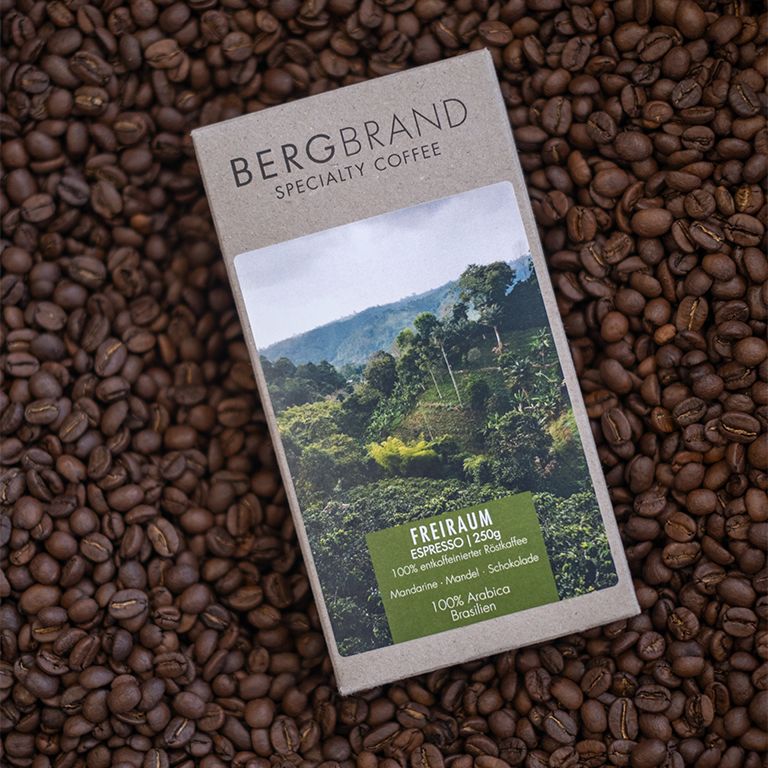 Kaffeepackung mit Landschaftsbild. Text: BERGBRAND, Freiraum Espresso, 100% Arabica, Brasilien, Decaf. Auf Kaffeebohnen.