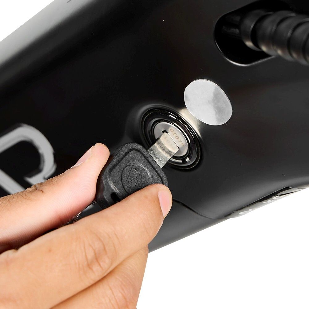 Nahaufnahme: Schlüssel wird in das Zündschloss eines schwarzen Elektrofahrrads gesteckt. Sichtbar: Schlüssel, Schloss, Fahrradrahmen.