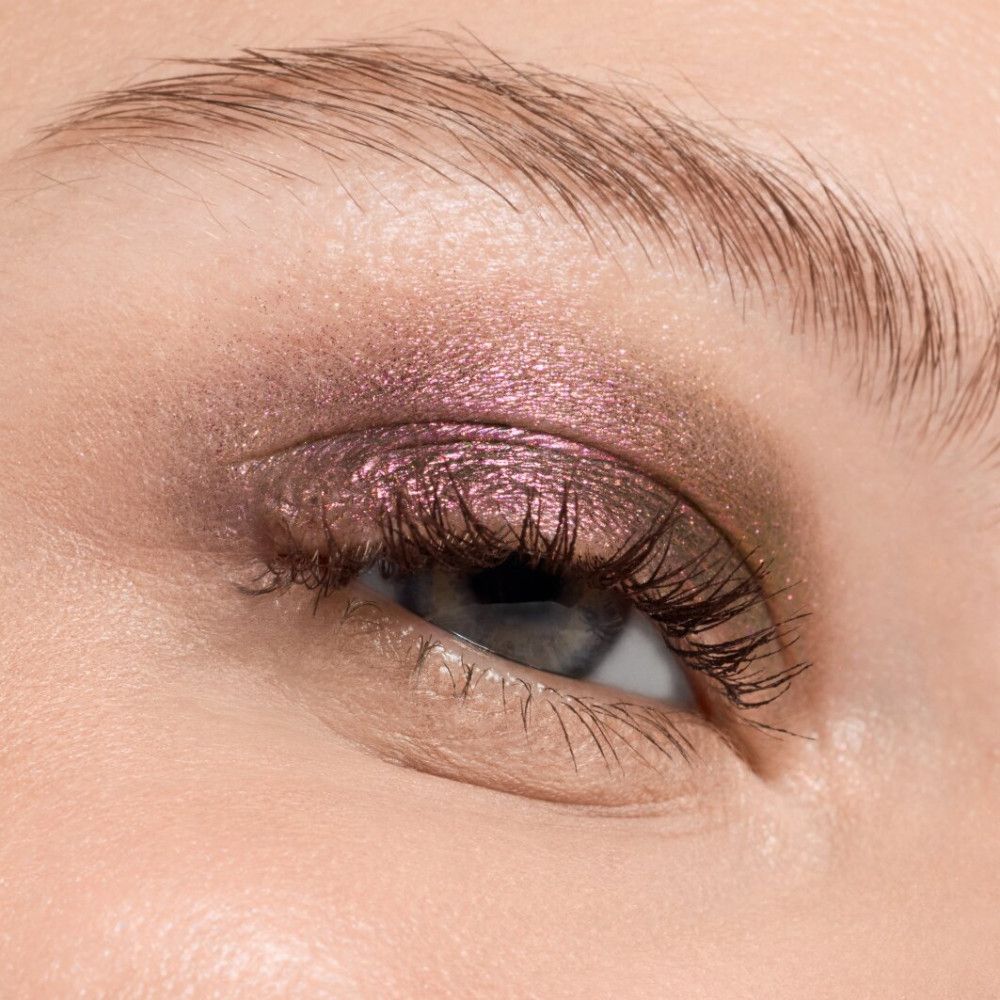 Nahaufnahme eines geschminkten Auges. Lidschatten in Rosa- und Brauntönen. Lange Wimpern.