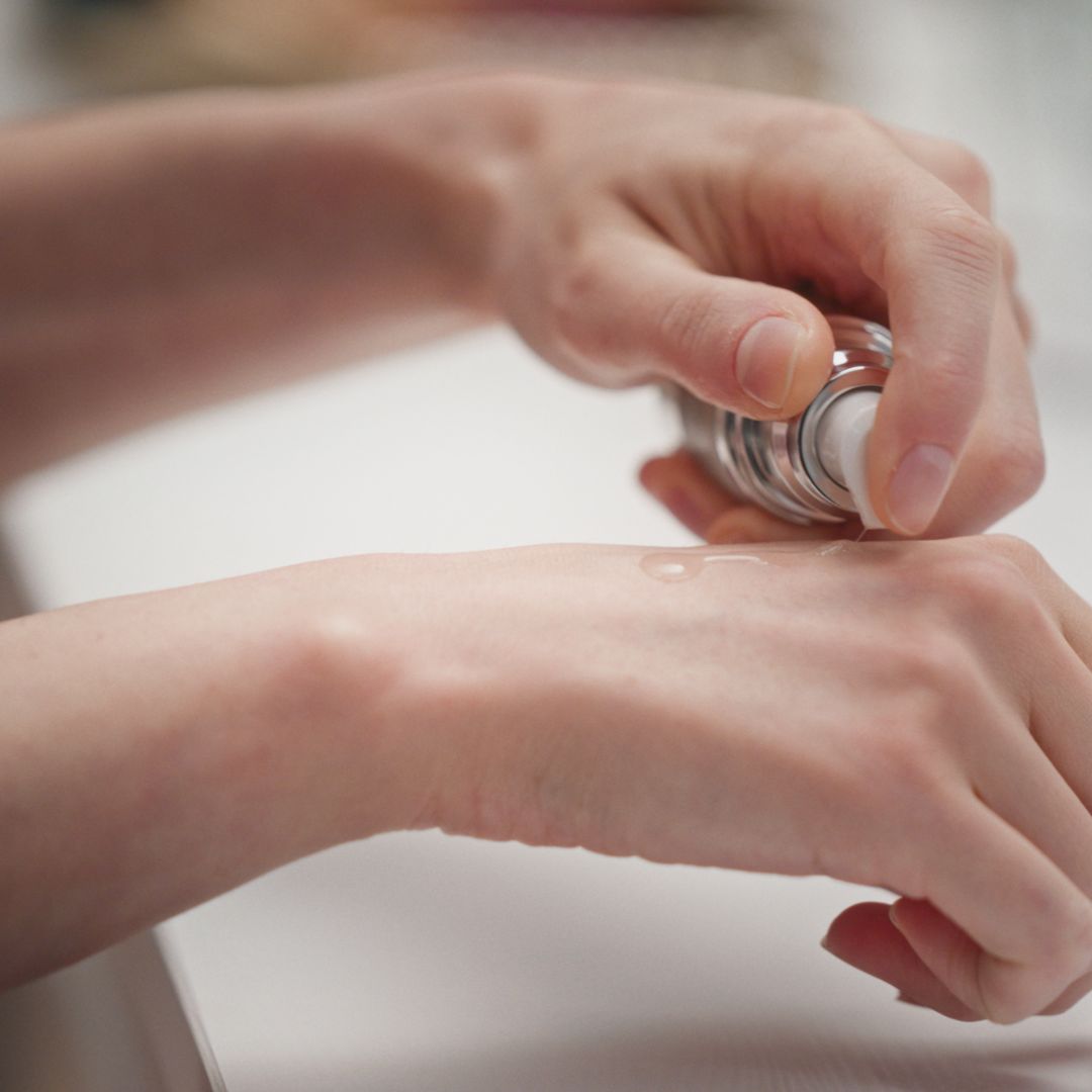 Hände, die Serum auf die Haut auftragen. Die Flasche ist nicht sichtbar.
