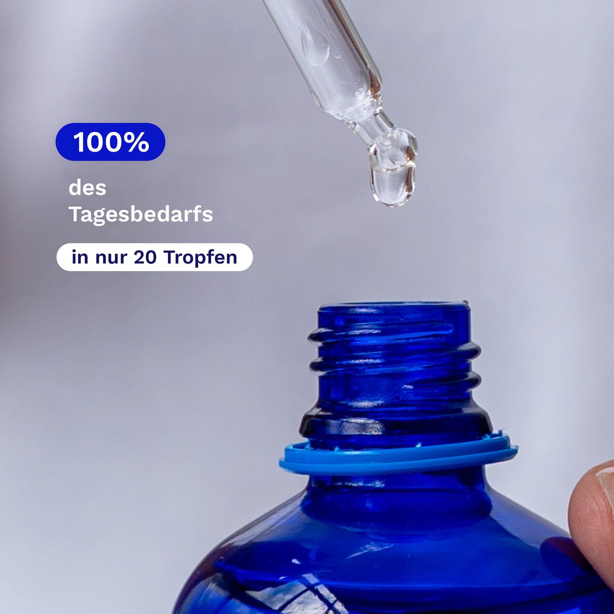 Pipette tropft Flüssigkeit in eine blaue Flasche. Text: 100% des Tagesbedarfs in nur 20 Tropfen.