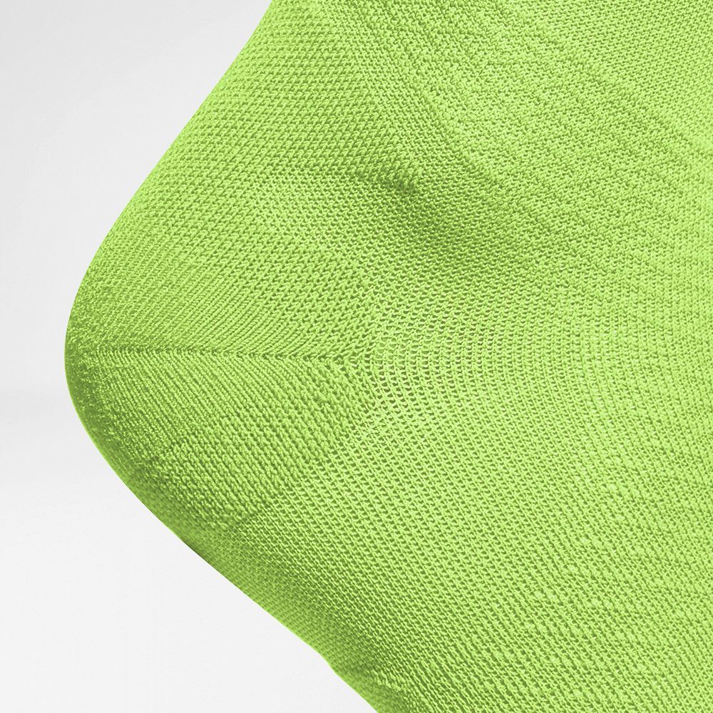Nahaufnahme der Ferse eines neongelben Kompressionssockens mit verstärkter Strickstruktur.