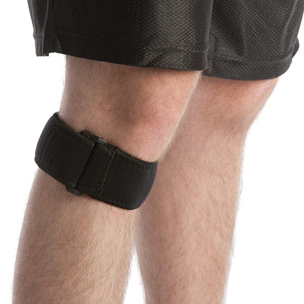 Schwarze Kniebandage mit Klettverschluss am Knie einer Person. Nahaufnahme, seitliche Ansicht.