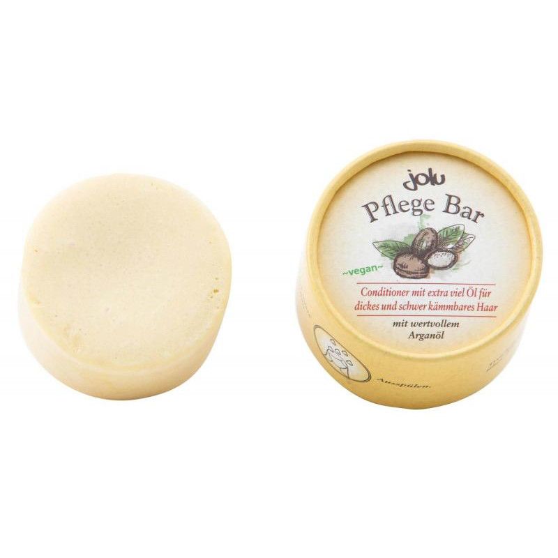 Runder Pflege Bar neben einer runden Pappschachtel. Auf der Schachtel steht "Jolu Pflege Bar" und "Conditioner für dickes und schwer kämmbares Haar".