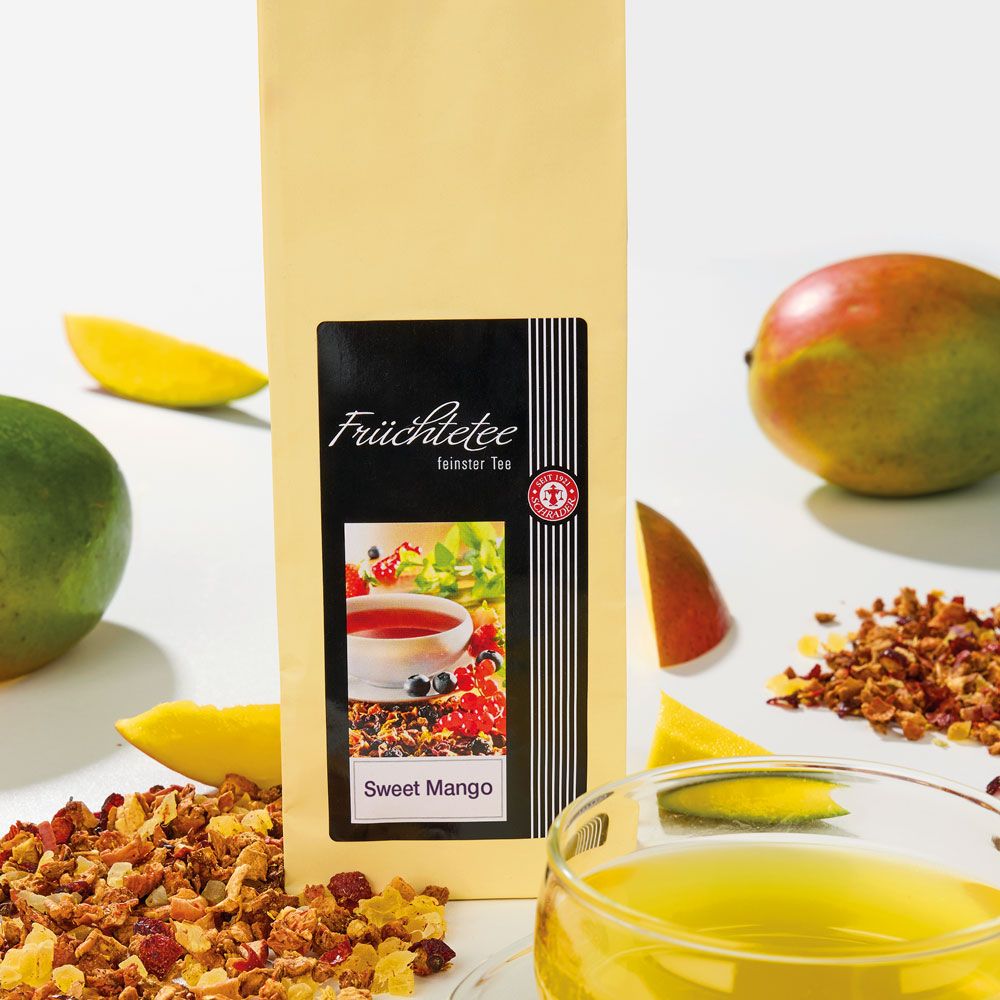 Beutel mit schwarzem Etikett. Aufschrift: Früchtetee, Sweet Mango. Mango-Früchte und Tee.