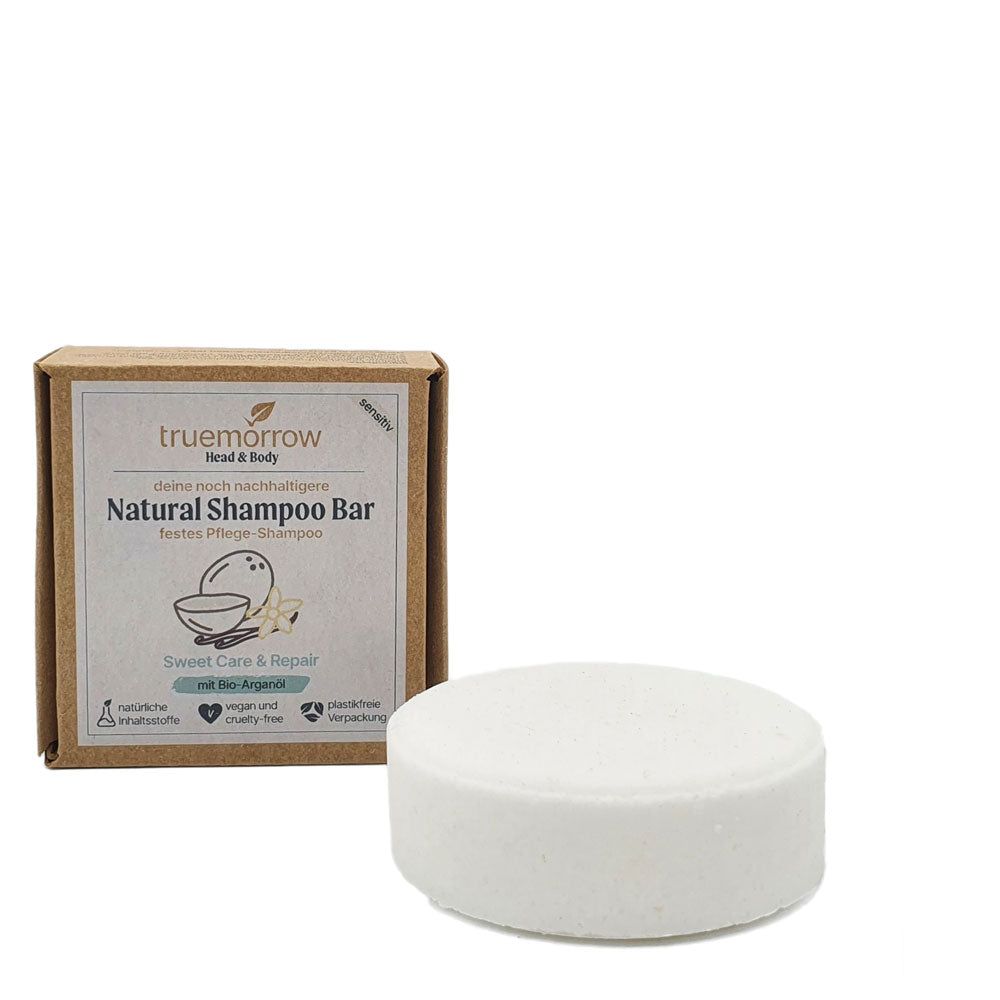 Runder, weißer Shampoo-Bar neben einer braunen Kartonverpackung. Auf der Verpackung steht "truemorrow Natural Shampoo Bar".