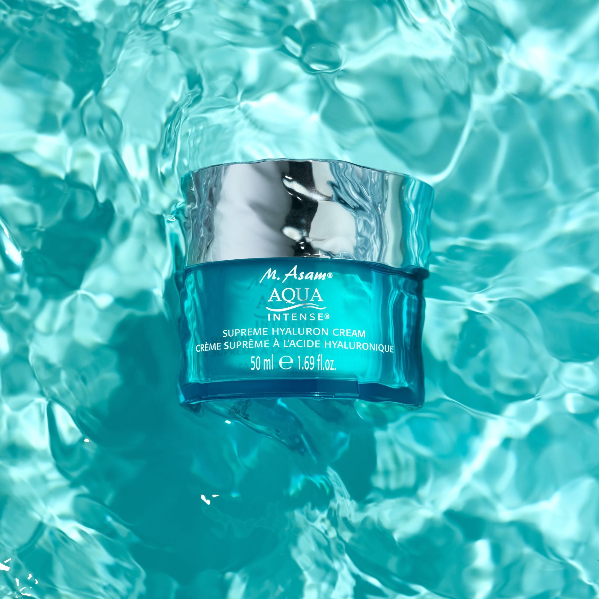 Product M. Asam Aqua Intense Supreme Hyaluron Cream in water. Turquoise glas, zilveren deksel. Tekst: Supreme Hyaluron Cream, 50 ml.
