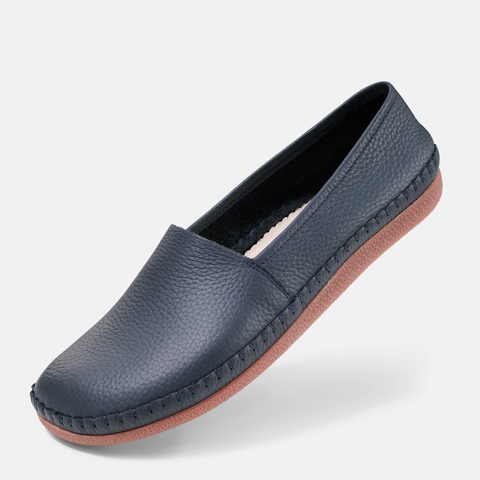 Blauer Unisex-Slipper mit breiter Passform. Sichtbare Nähte und braune Sohle. Obermaterial mit Lederstruktur.