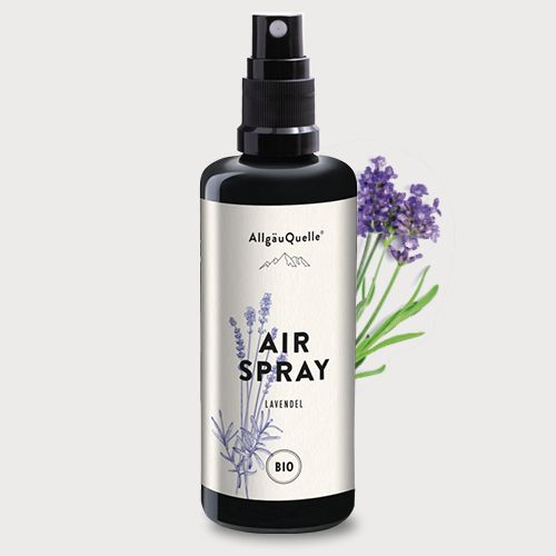 Schwarze Sprühflasche mit Etikett. Aufschrift: Air Spray Lavendel, Bio. Neben der Flasche: Lavendelblüten.