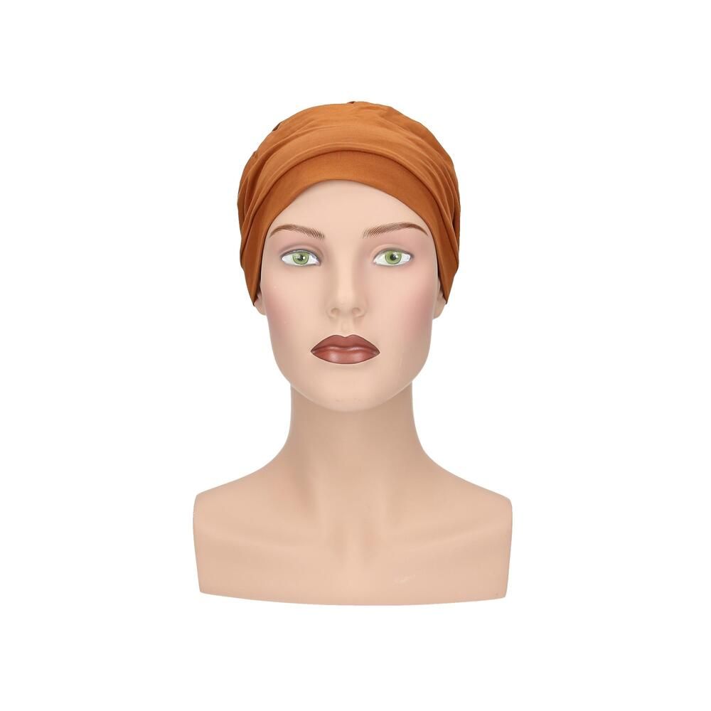 Ockerfarbener Turban auf einer Schaufensterpuppe. Frontansicht. Stoff mit Falten. Keine weiteren Details.