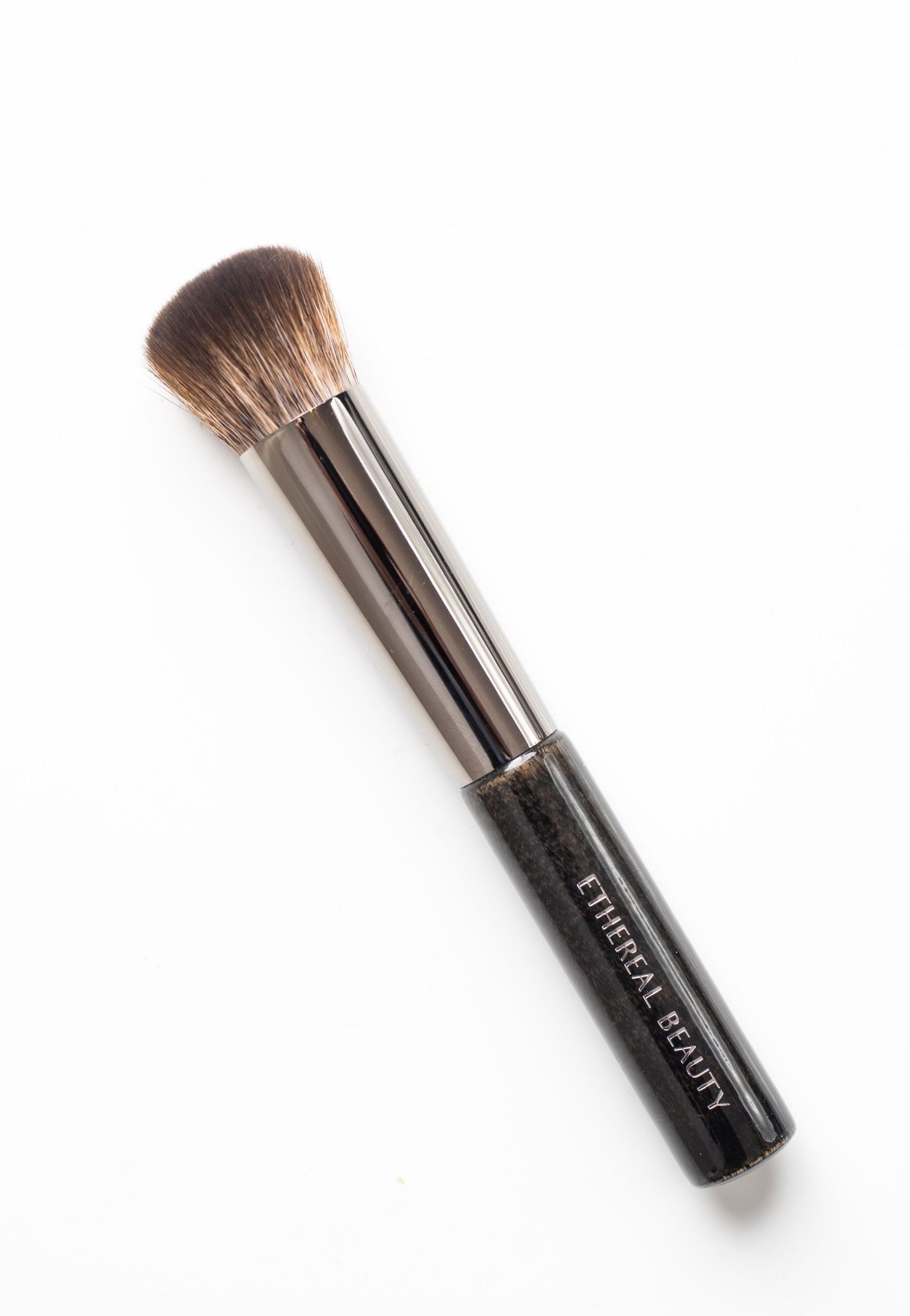 Foundationpinsel mit dunklem Griff und braunen Borsten. Ethereal Beauty-Logo auf dem Griff. Auf weißem Hintergrund.