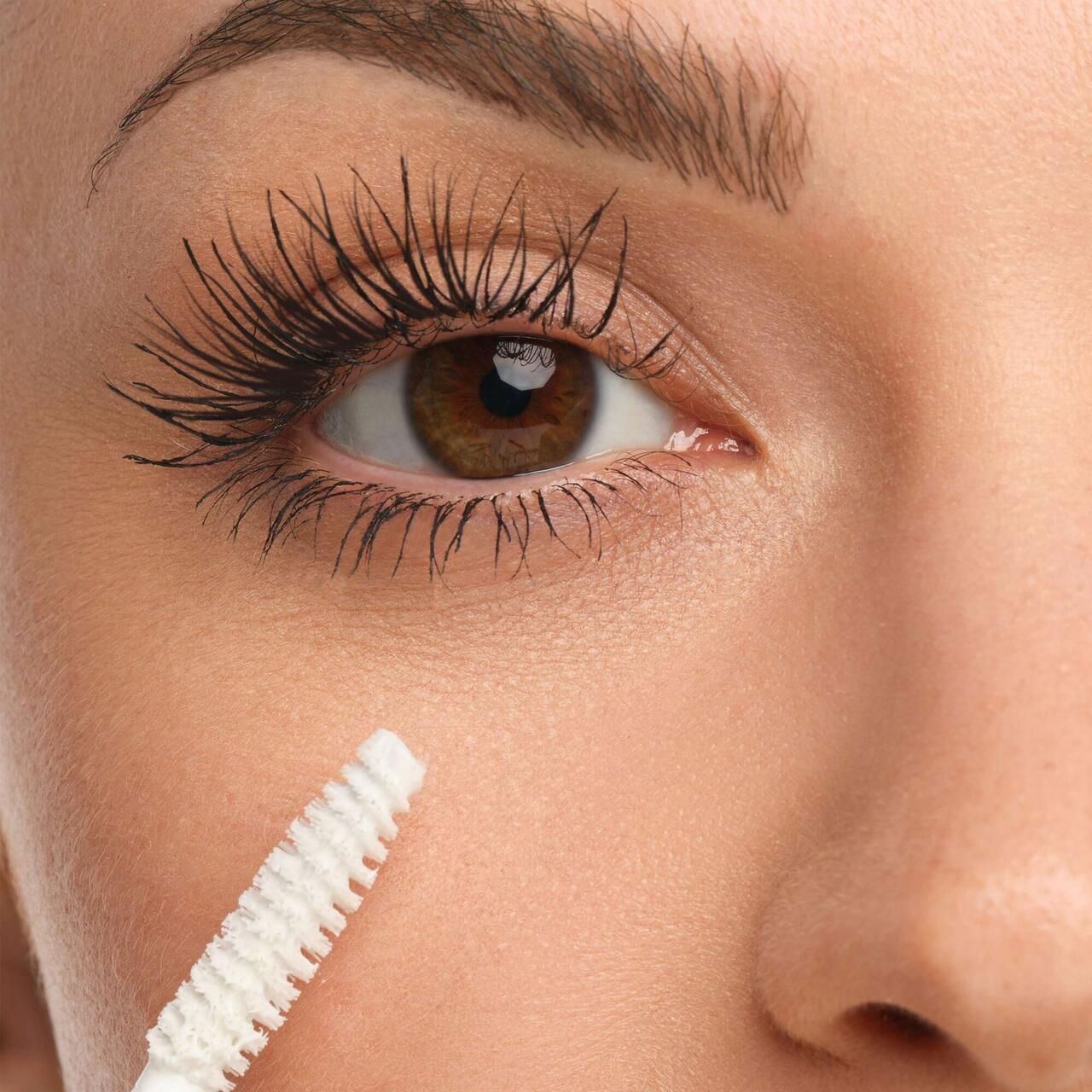 Auge mit getuschten Wimpern. Bürste in der Nähe des Auges.