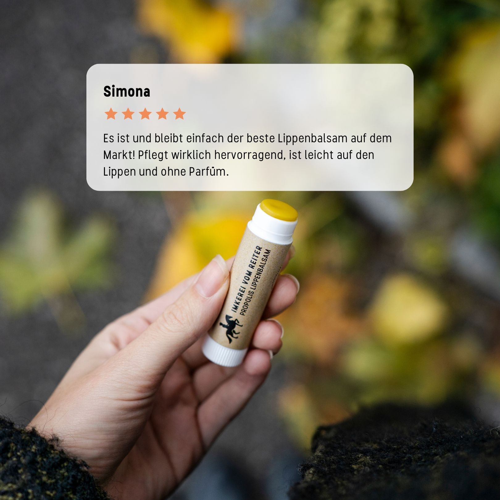 Hand hält Lippenbalsam-Stift. Textblase: Simona, 5 Sterne. Text: bester Lippenbalsam, pflegt hervorragend, leicht auf Lippen, ohne Parfum.