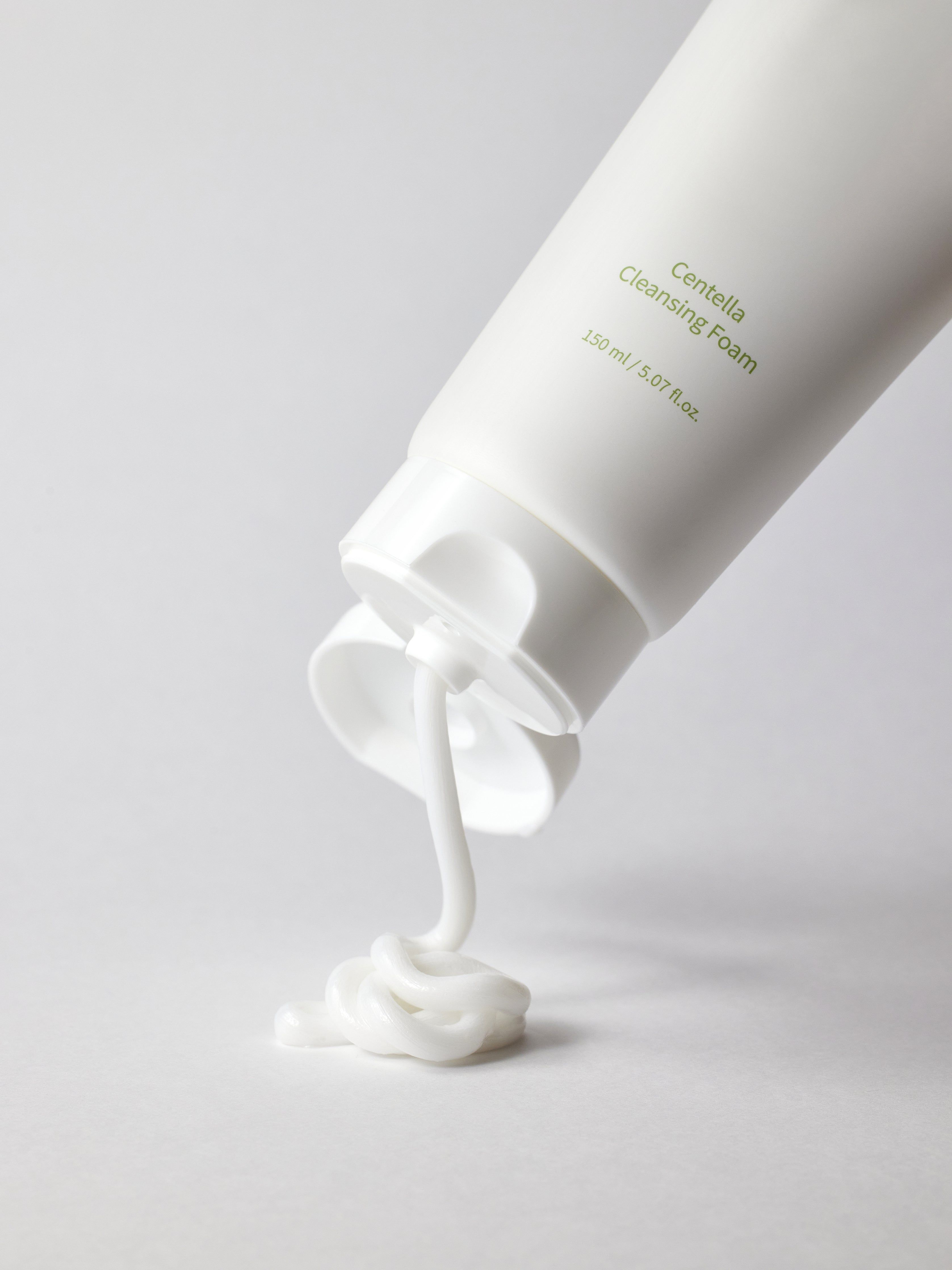 Weiße Tube, aus der weiße Reinigungsschaum herausfließt. "Centella Cleansing Foam"-Schriftzug. 150 ml.
