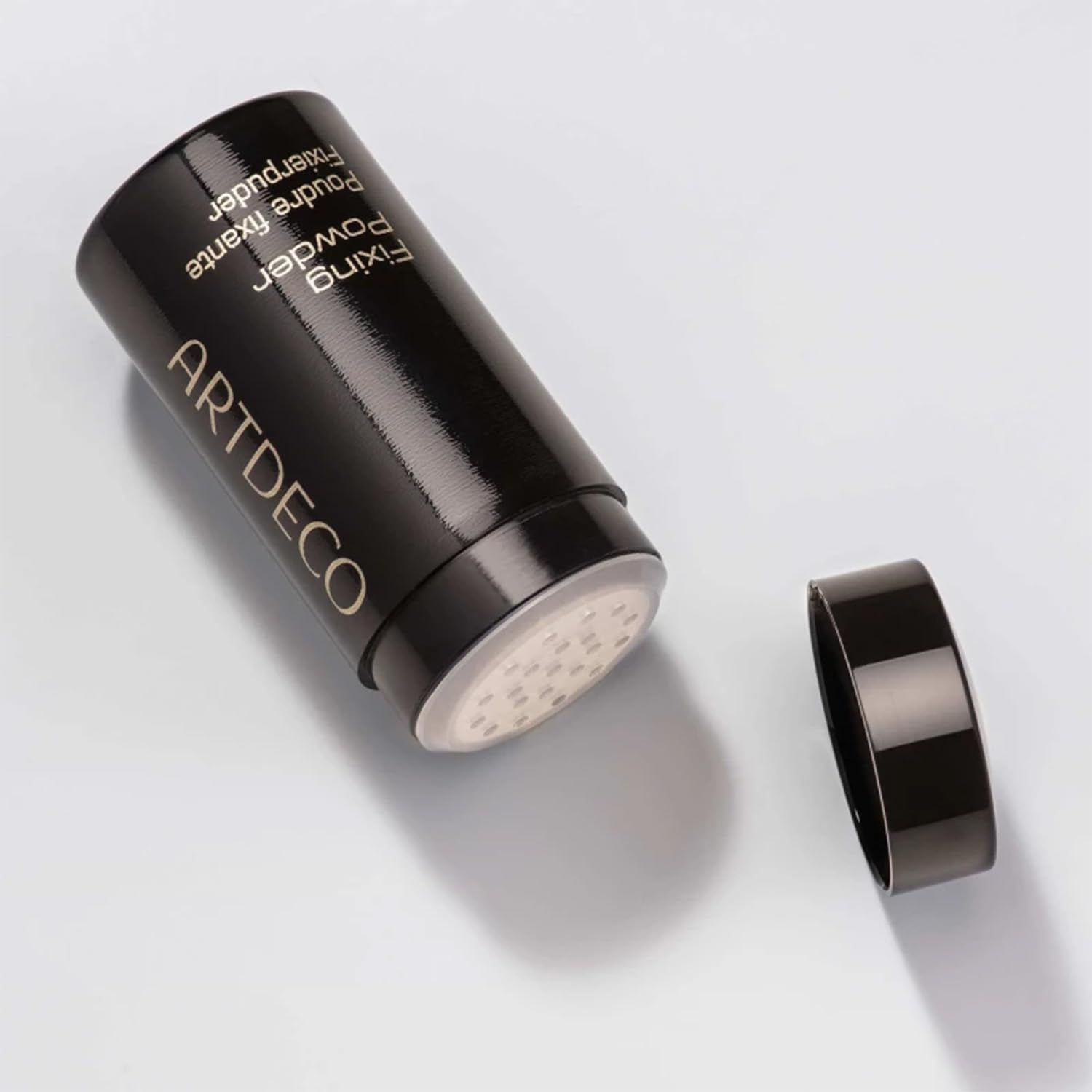 Schwarzer Artdeco Fixierpuder-Behälter, geöffnet. Aufschrift: Fixing Powder, Poudre fixante, Fixierpuder.