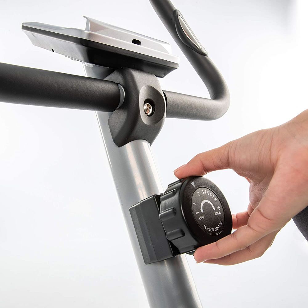 Nahaufnahme eines Drehreglers zur Widerstandseinstellung am Heimtrainer. Die Hand dreht den Regler.