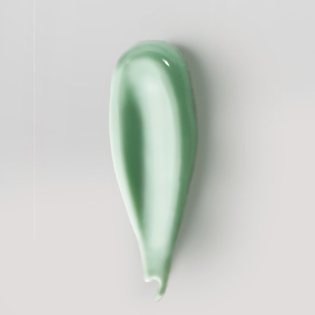 Grüner Cremestrich auf hellem Hintergrund. Die Creme hat eine glatte Textur und eine längliche Form.