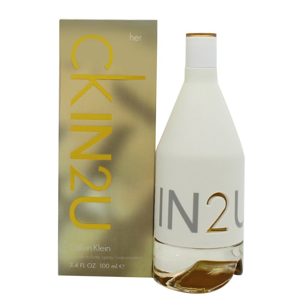 Parfümflasche und Verpackung. Flasche weiß, zylindrisch, mit silbernem Schriftzug. Verpackung goldfarben mit gelbem Schriftzug.