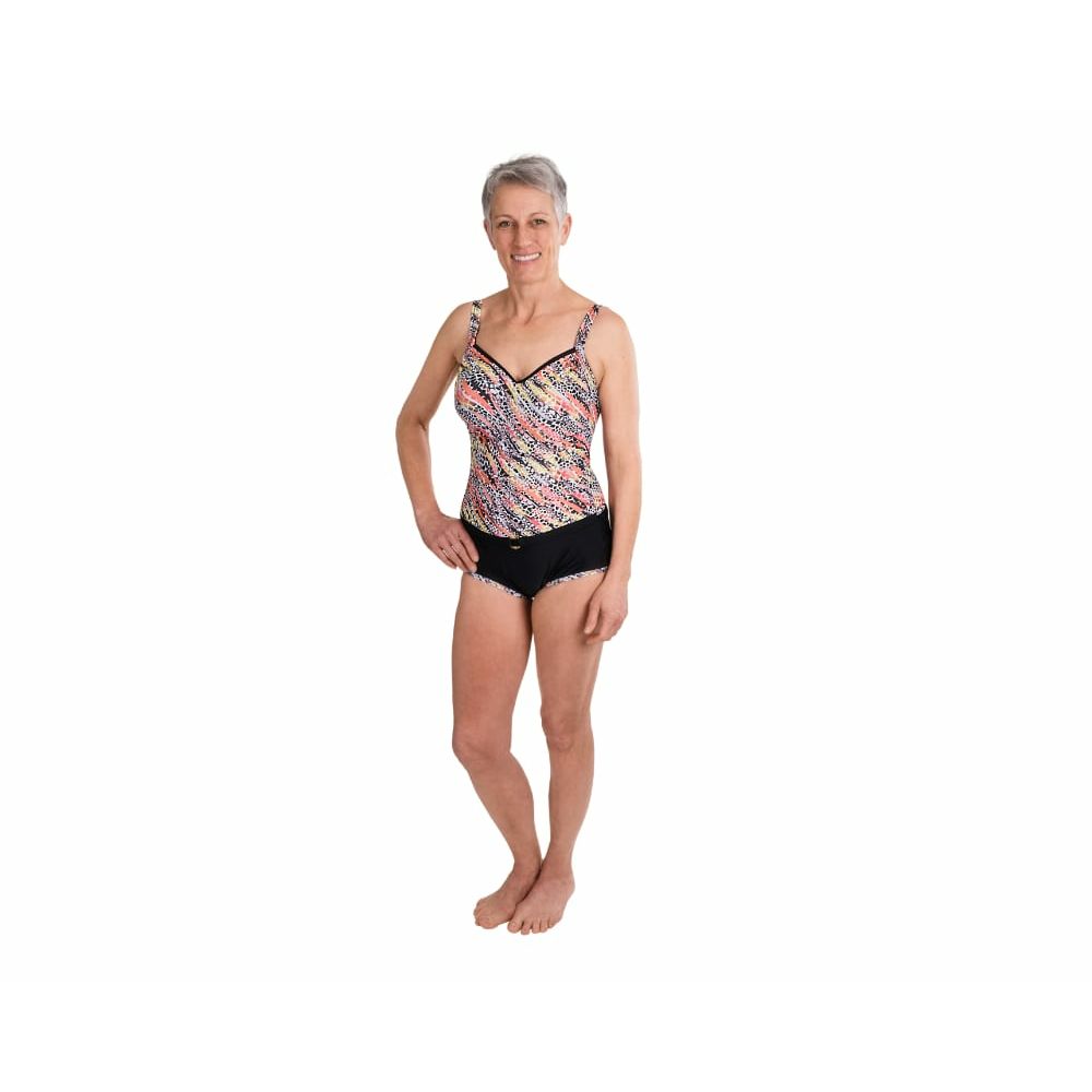 Frau im Badeanzug-Set: Oberteil mit Muster, schwarzer Slip. Steht, lächelt.