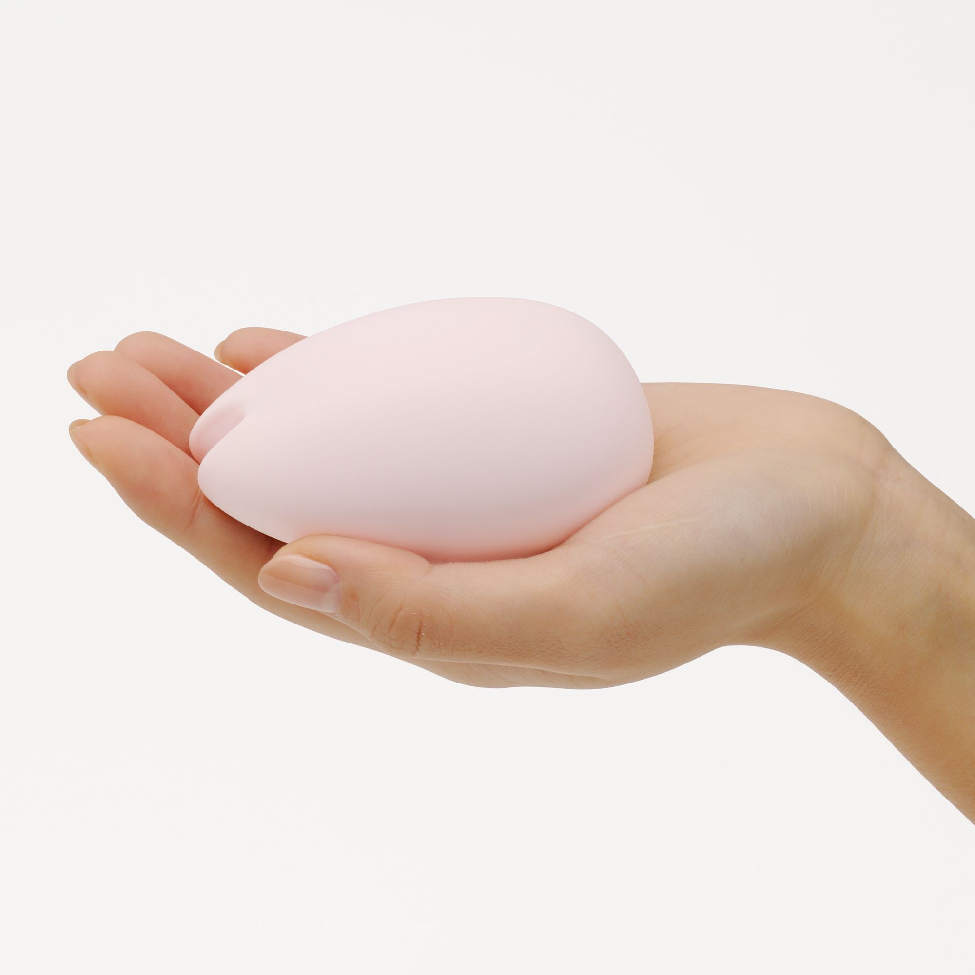 Rosa TENGA iroha SAKURA Vibrator in einer Hand gehalten. Eiförmig, mit Aussparung.
