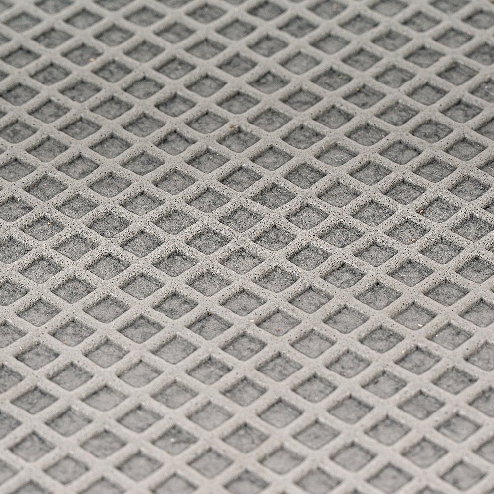 Nahaufnahme der grauen, geriffelten Oberfläche eines Karussell-Elements. Quadratisches Muster, rutschfeste Oberfläche.