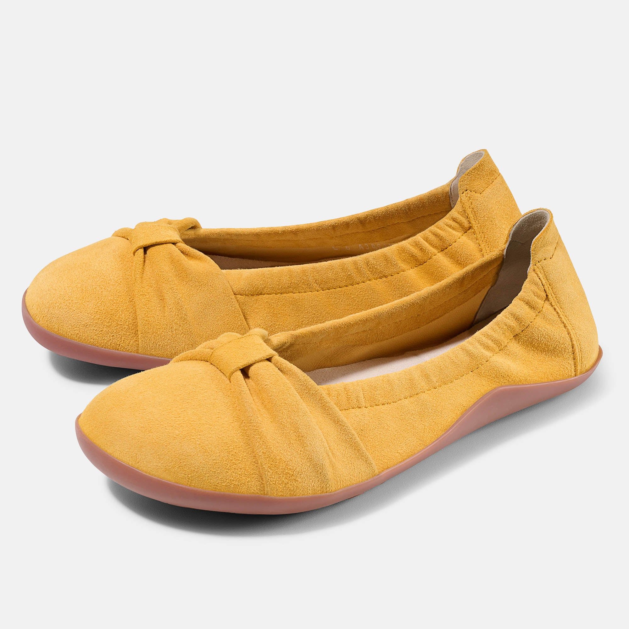 Zwei gelbe Ballerinas. Obermaterial aus Wildleder, runde Zehen, Schleife vorne. Rosa Sohle. Weite Form.