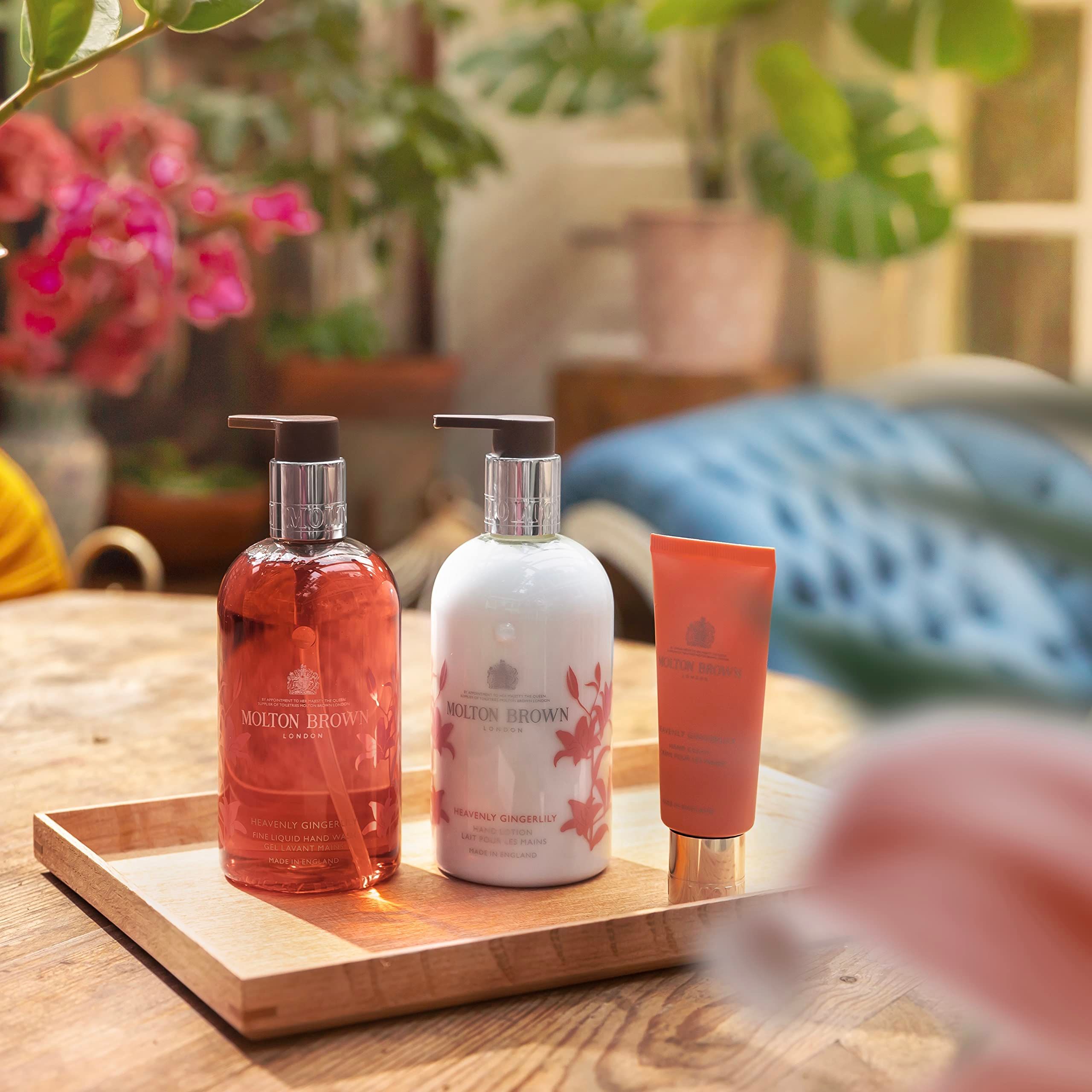 Holztablett mit drei Produkten: Rote und weiße Flüssigseife, sowie eine Tube. Aufschrift: Molton Brown. Im Hintergrund Pflanzen.