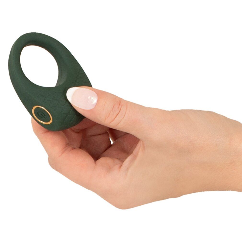 Dunkelgrüner Penisring, gehalten von einer Hand. Mit Bedienknopf.