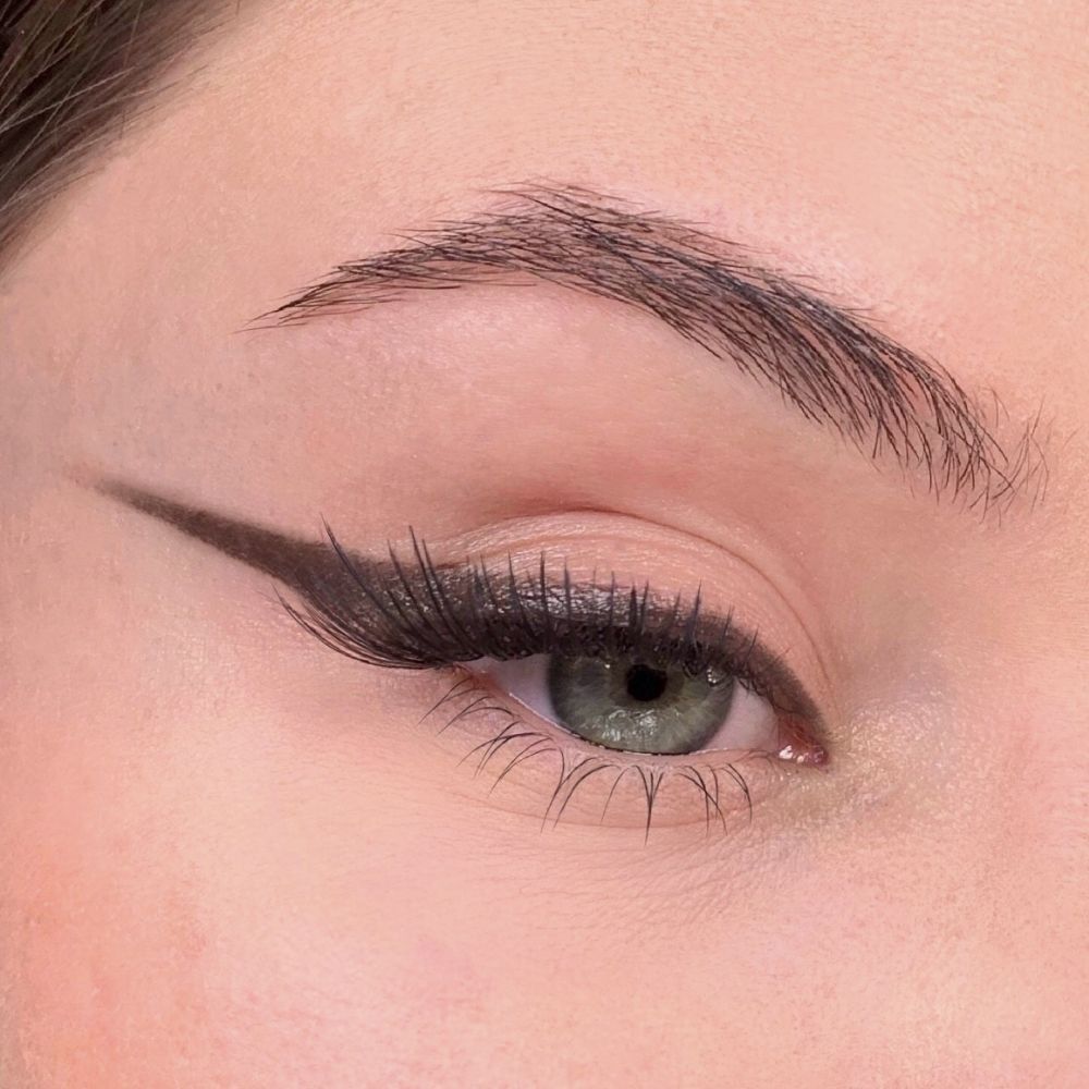 Auge mit braunem Eyeliner. Brauner Eyeliner auf dem Augenlid. Braune Wimpern. Augenbraue.