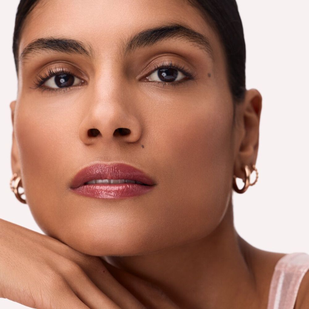 Porträt einer Frau mit Lip Tint auf den Lippen. Rosa Farbton. Goldene Ohrringe.