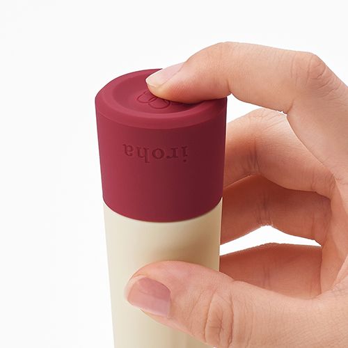 Nahaufnahme des Vibrator-Endes. Roter Sockel mit "iroha"-Schriftzug, Finger berühren die Oberfläche.