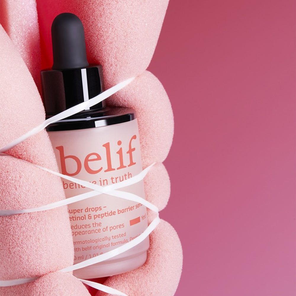 Hände halten Belif Super Drops Serum Flasche, umwickelt mit Band.