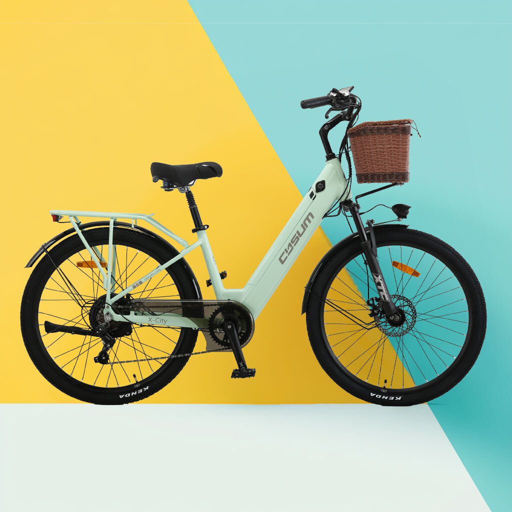 Hellgrünes Elektrofahrrad mit Korb, schwarzem Sattel und Reifen. Gelb-blauer Hintergrund.