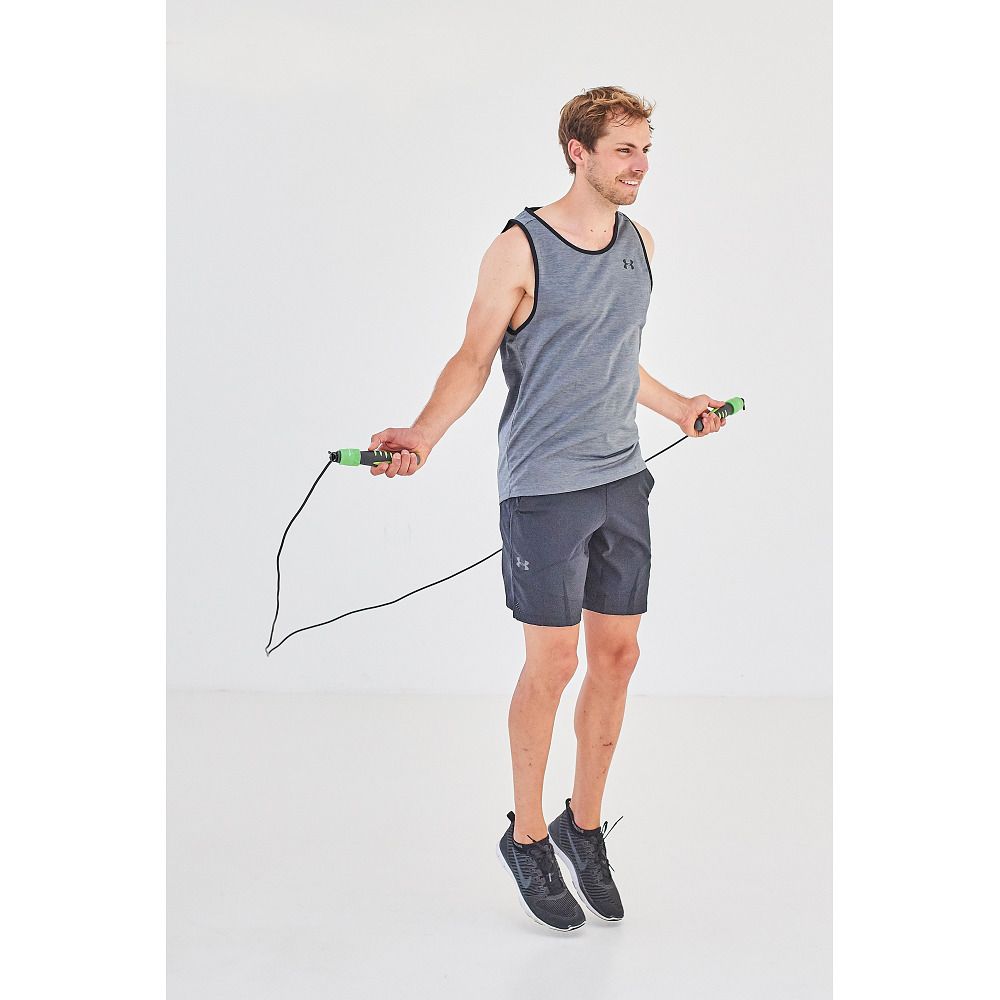 Mann springt mit einem schwarzen Springseil. Griffe grün. Person trägt Sportkleidung.