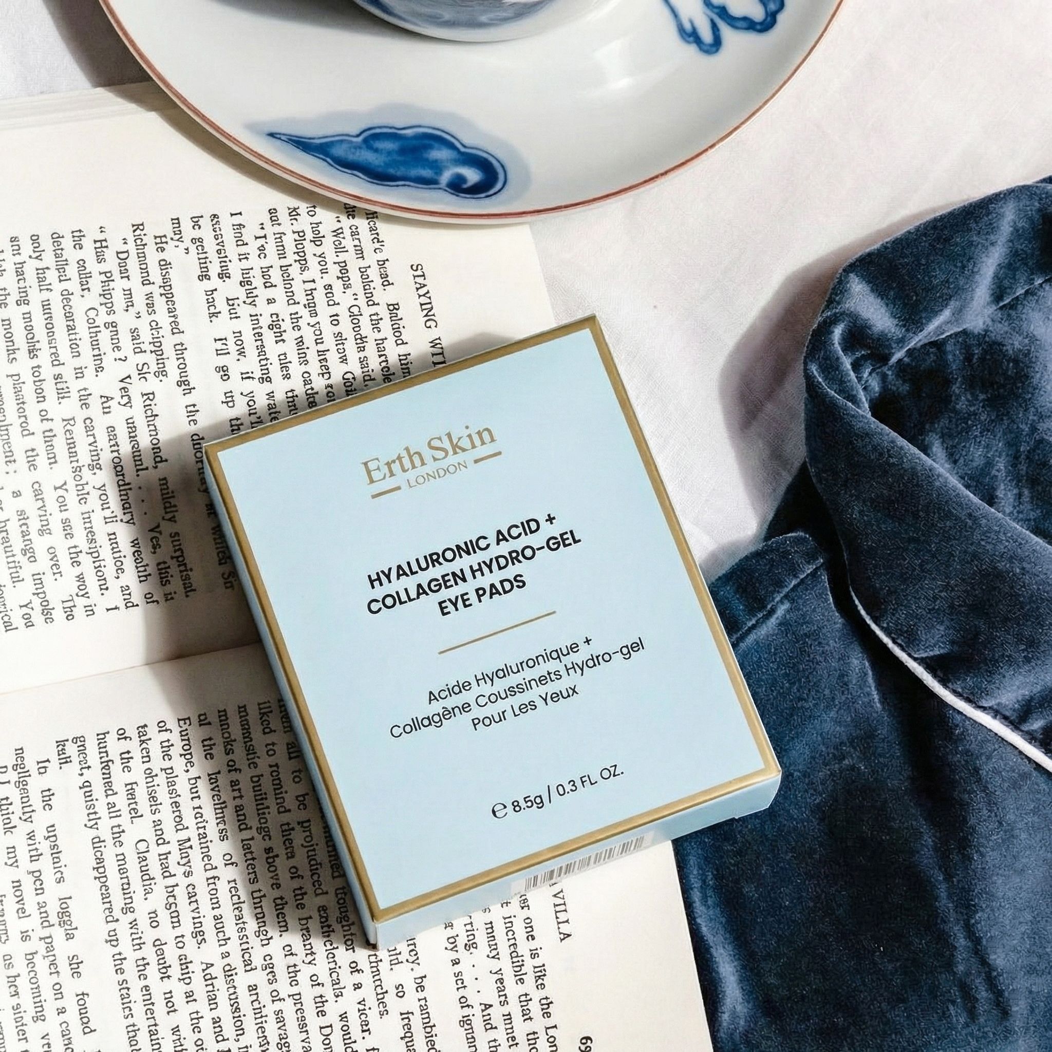 Verpackung der ErthSkin London Hyaluronsäure + Kollagen Hydrogel-Augenpads, auf einem Buch liegend.