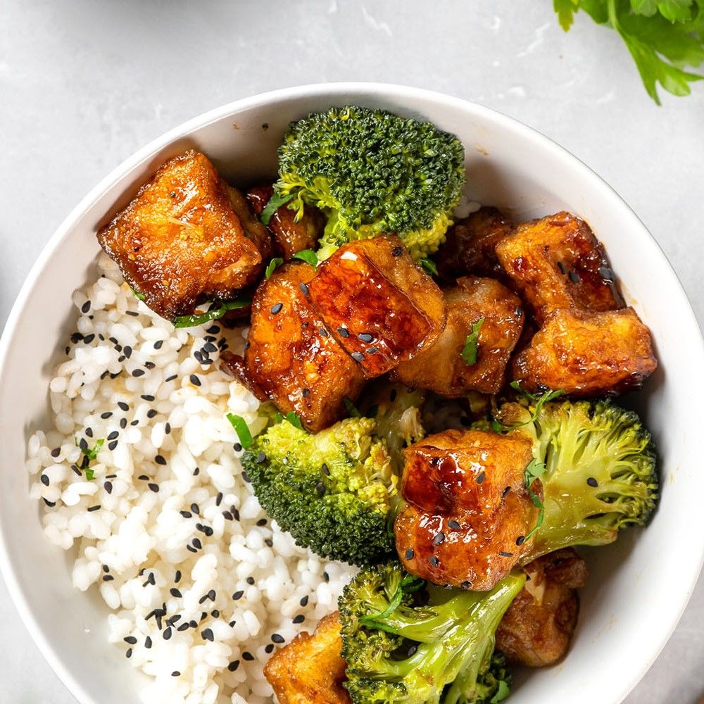Gebratener Tofu mit Brokkoli und Sesam auf Reis in einer Schüssel. Draufsicht.