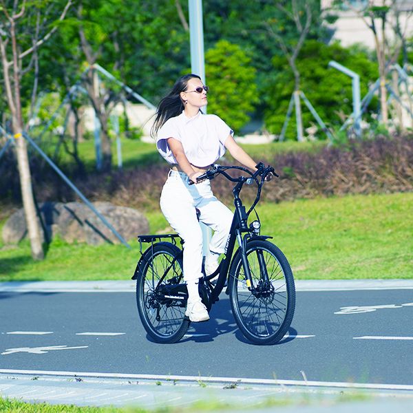 Schwarzes E-Bike mit Person. Person trägt weiße Kleidung und Sonnenbrille. Fährt auf einer Straße im Freien.