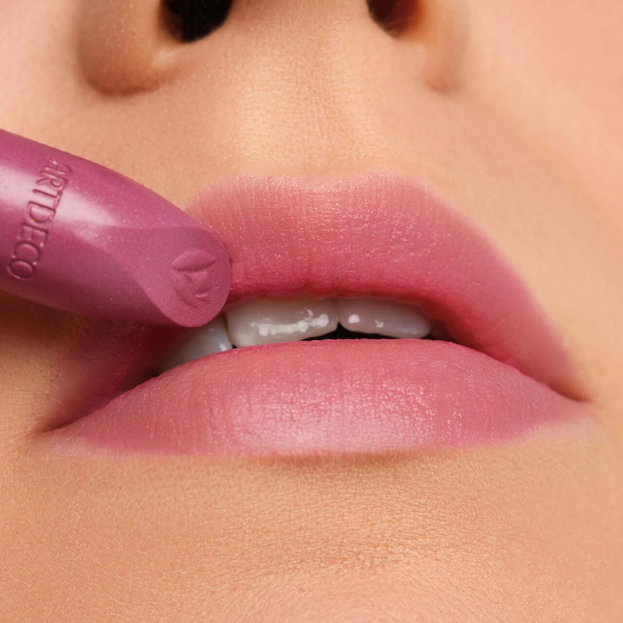 Lippenstift wird auf Lippen aufgetragen. Rosa Farbton. Marke Artdeco sichtbar. Nahaufnahme.