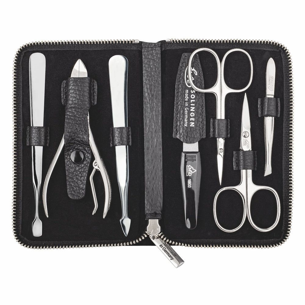 Offenes schwarzes Etui mit 7 glänzenden Metall-Maniküre-Instrumenten, darunter Schere, Pinzette und Nagelhautschieber.