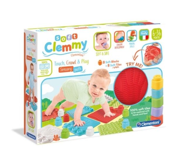 Verpackung mit Clemmy-Spielmatte. Enthält weiche Blöcke, Fliesen und einen roten Ball. Baby krabbelt auf der Matte. Text: Soft Clemmy, 6-36 Monate.