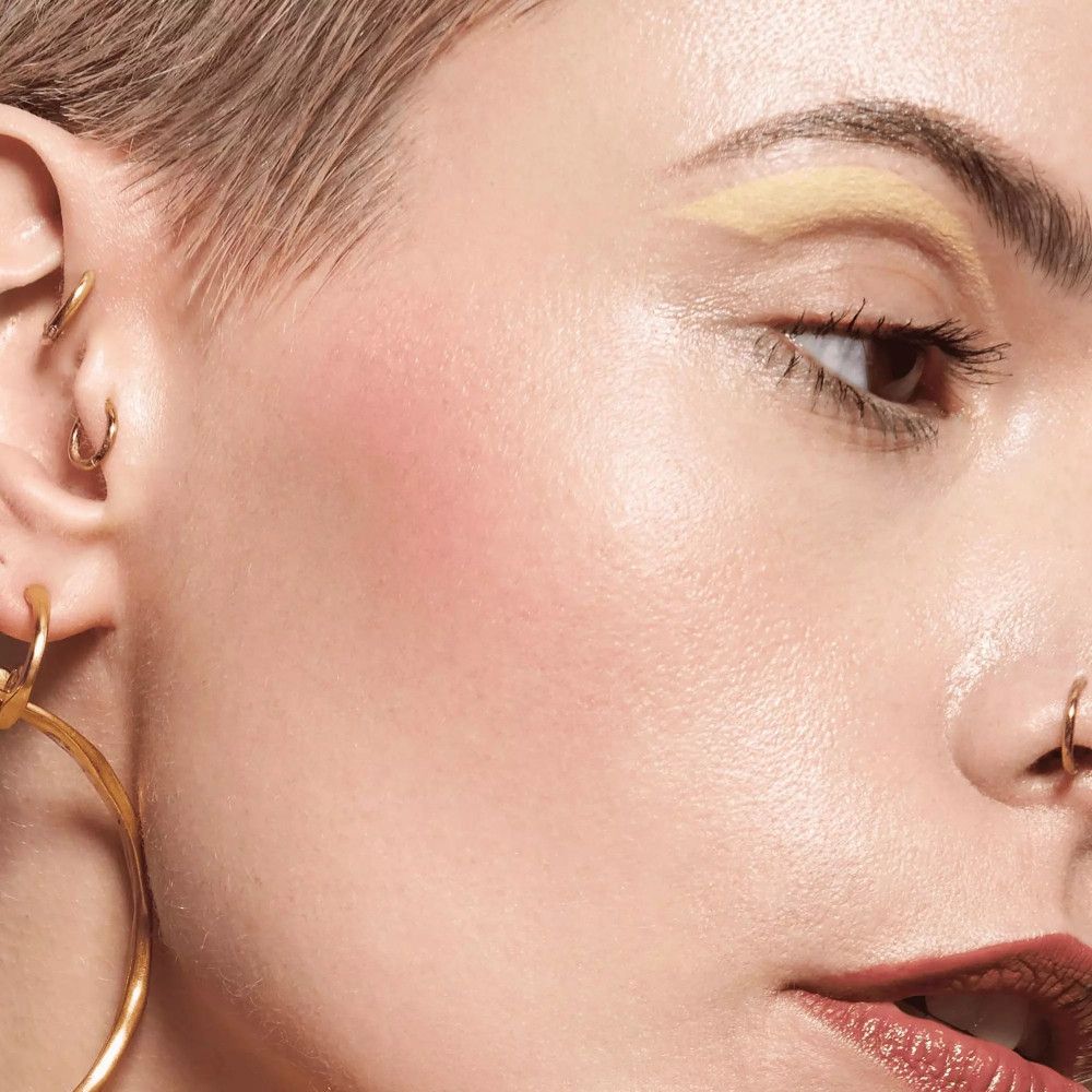 Nahaufnahme eines Gesichts mit Rouge auf den Wangen. Frau mit Ohrringen.