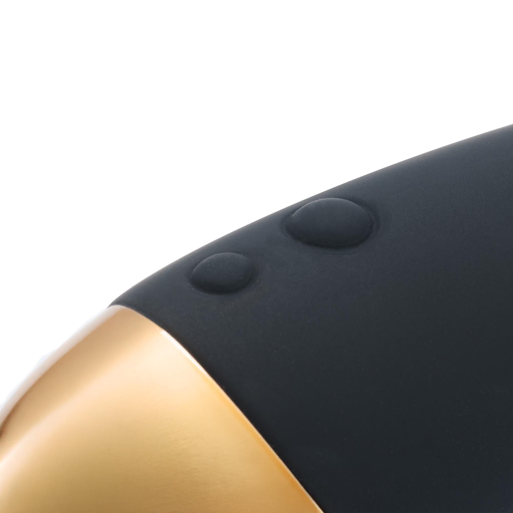 Nahaufnahme eines schwarzen Massage-Wands mit zwei erhabenen Knöpfen und einem goldfarbenen Akzent.